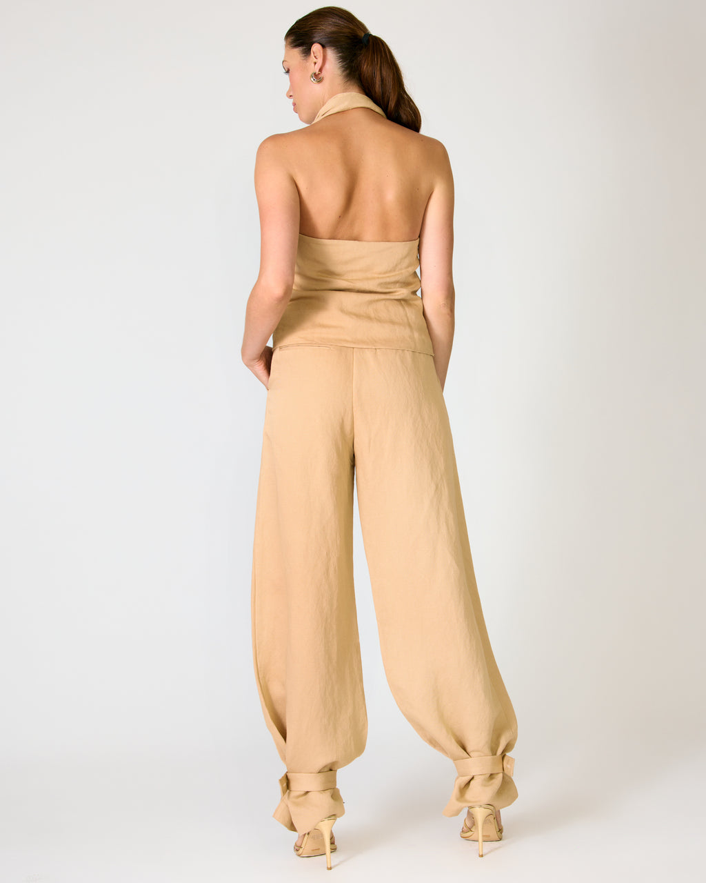 Woman wearing a beige strapless jumpsuit on a white background