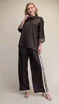 Woman wearing a patterned top and pants with a beige background