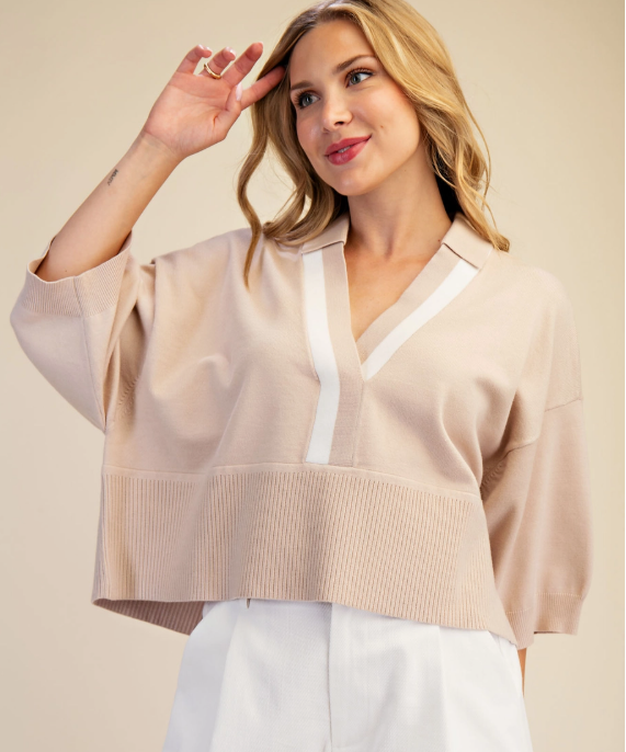 Woman wearing a slightly cropped collared sweater top in beige and white stripe