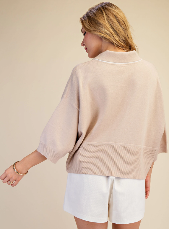 Woman wearing a slightly cropped collared sweater top in beige and white stripe
