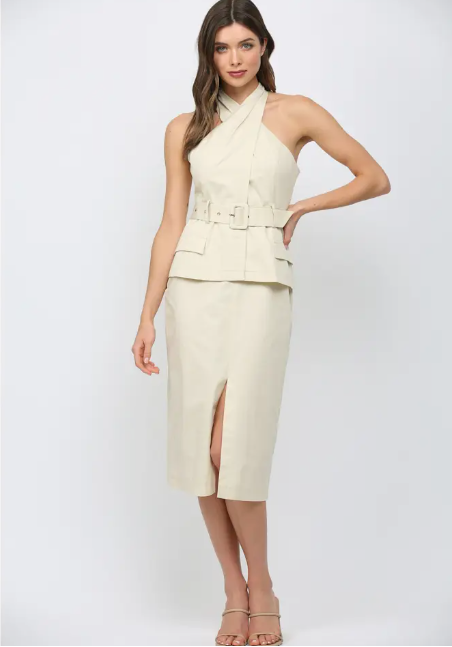 Woman wearing a cream-colored dress with a belt on a white background