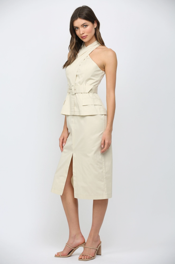 Woman wearing a light-colored dress with a halter top and skirt on a white background