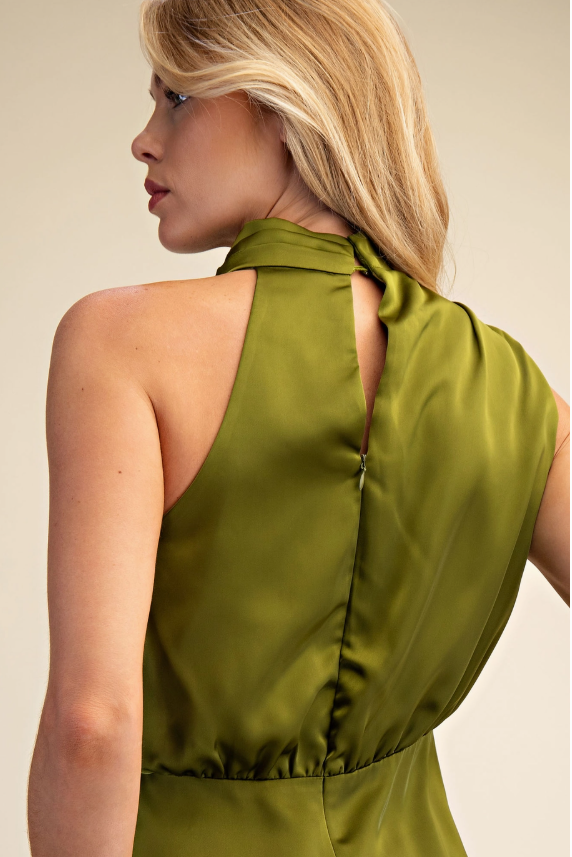Woman wearing a green halter neck top against a beige background