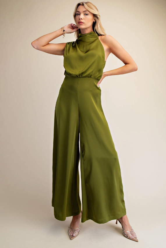 Woman wearing a green jumpsuit against a beige background